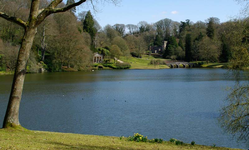 View across lake to Temple of Flora, the Palladian Bridge and St Peter's Church - Stourhead Gardens